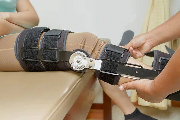 Orthopedist secures leg brace on knee
